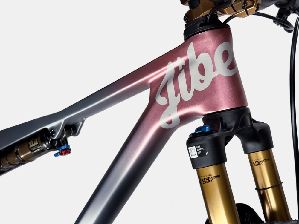 Close-up of a grey and pink bicycle frame with 'Jibe' branding on a white background