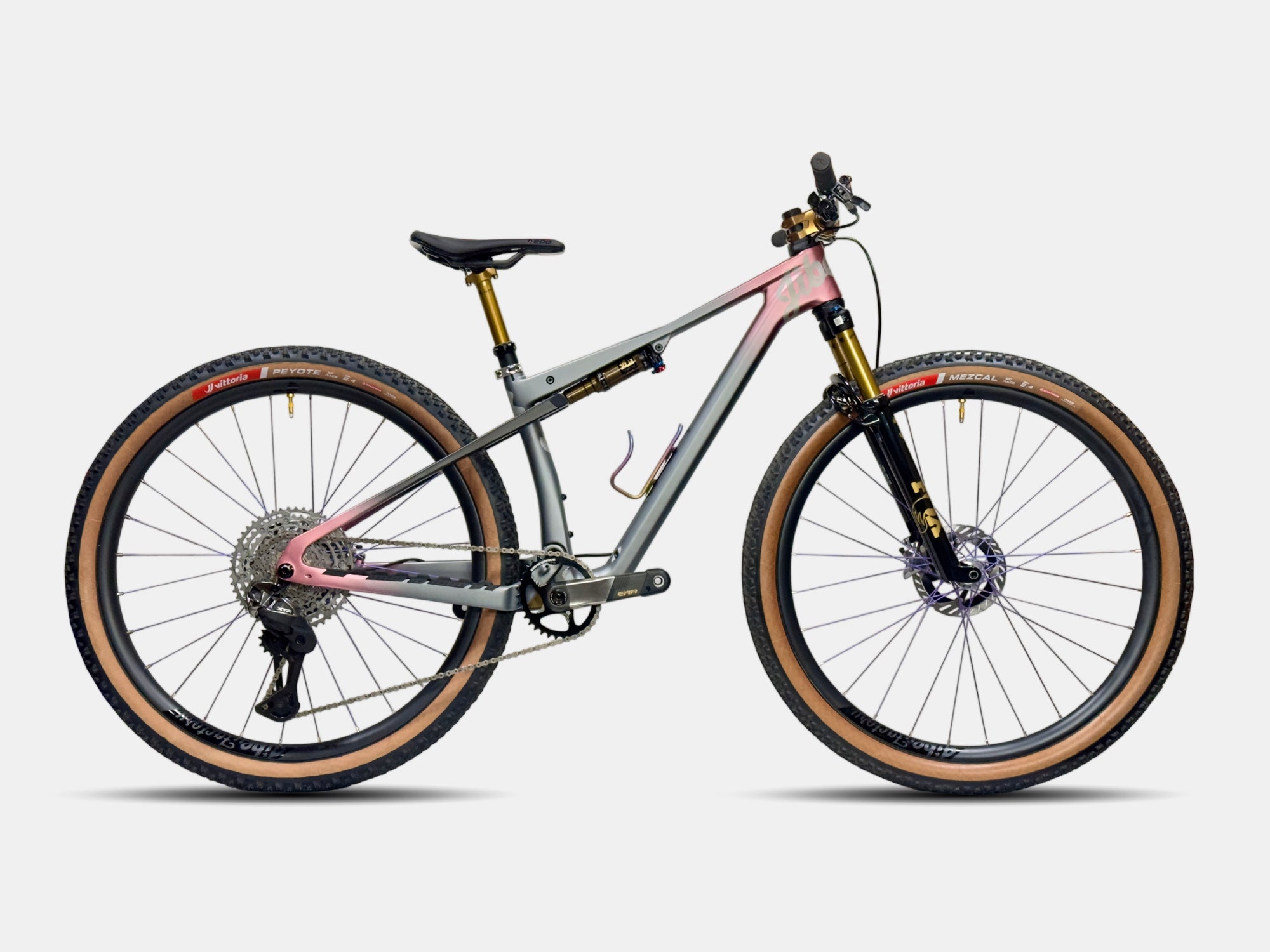 The Jibe Tasmanian Devil Bike. Grey and rose gold/pink on the tips of the bike. Kashima/gold accents. Brown wall tires. 