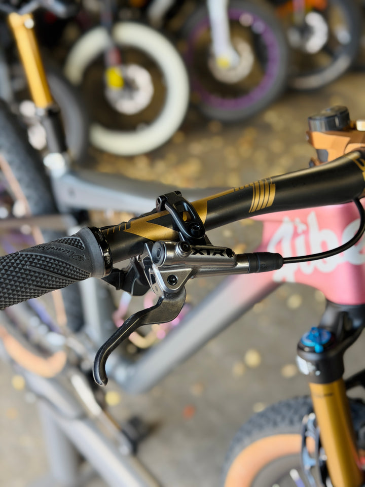 Close-up of bicycle handlebars with visible brake levers and grip on a blurred background of other bikes.