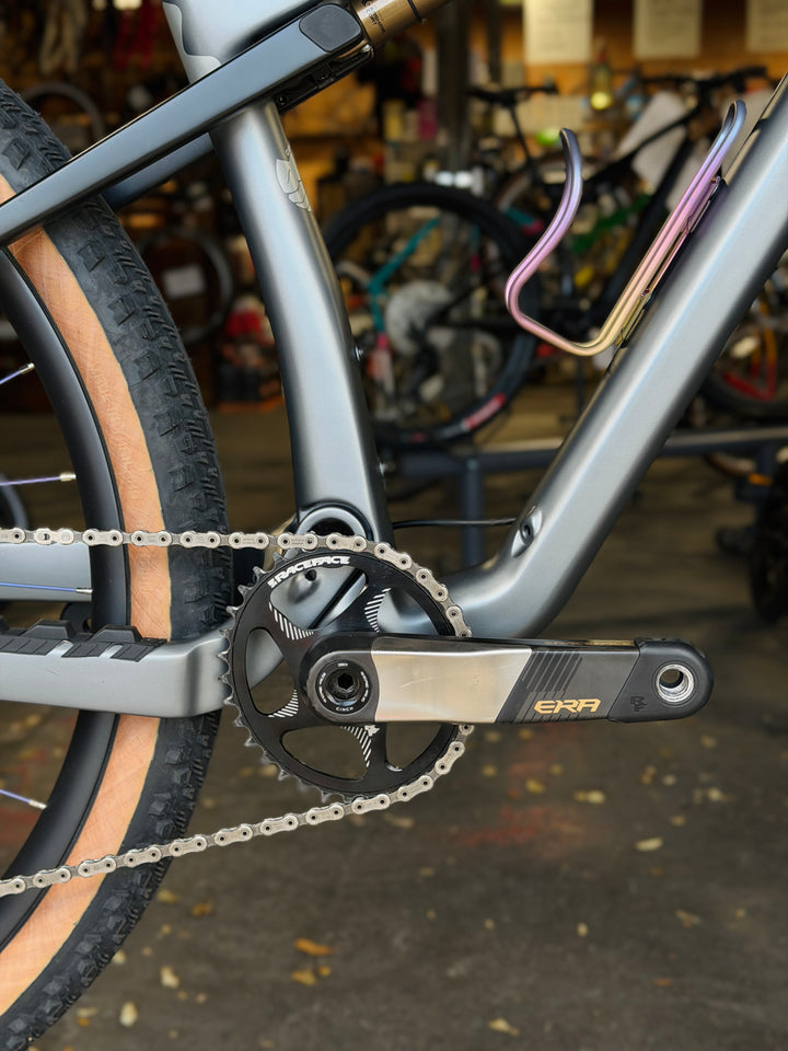 Close-up of a bicycle chain and gear system (XTR Di2) with a blurred background of a bike shop.