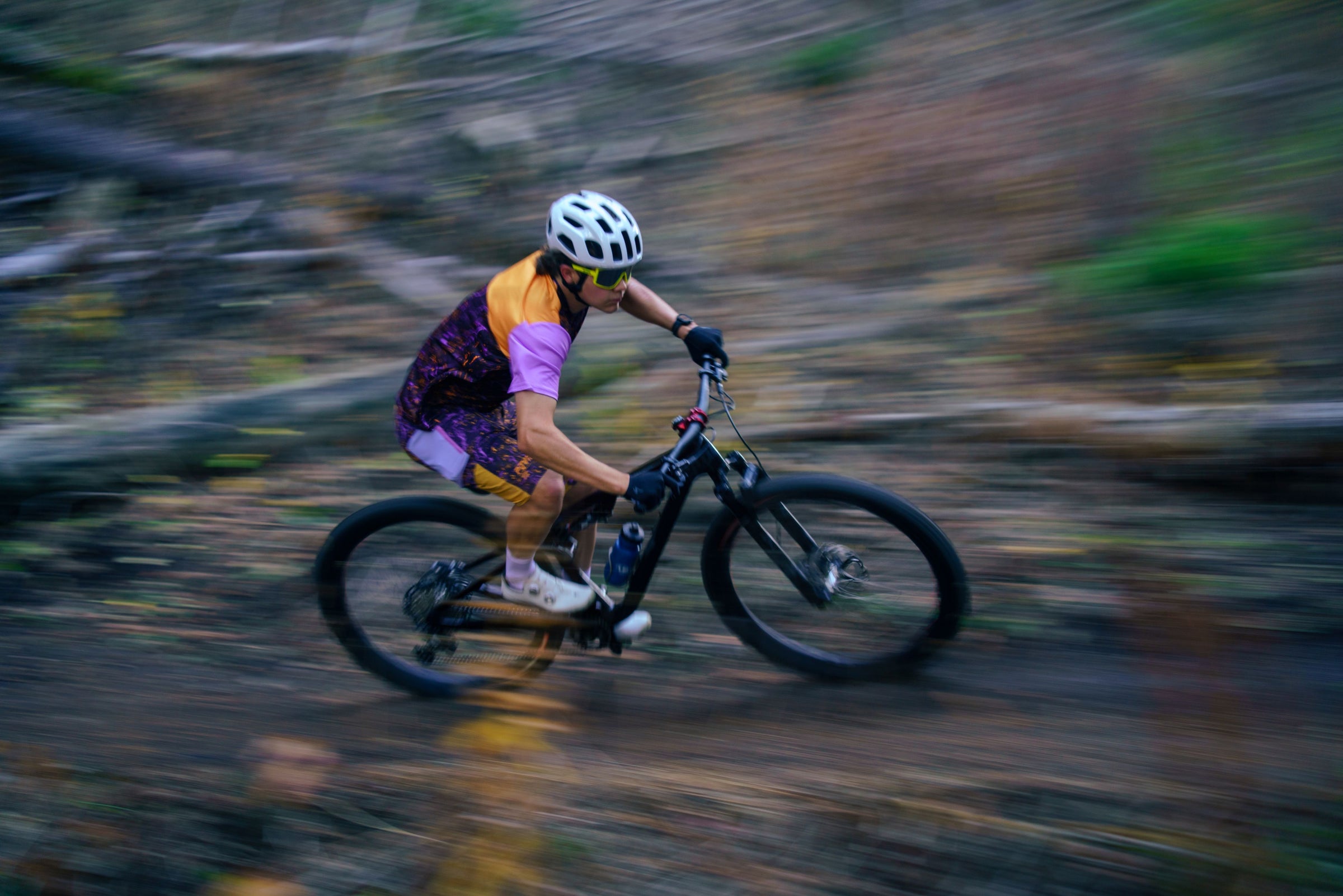 Person riding a Jibe Jester mountain bike on a trail with a blurred background.